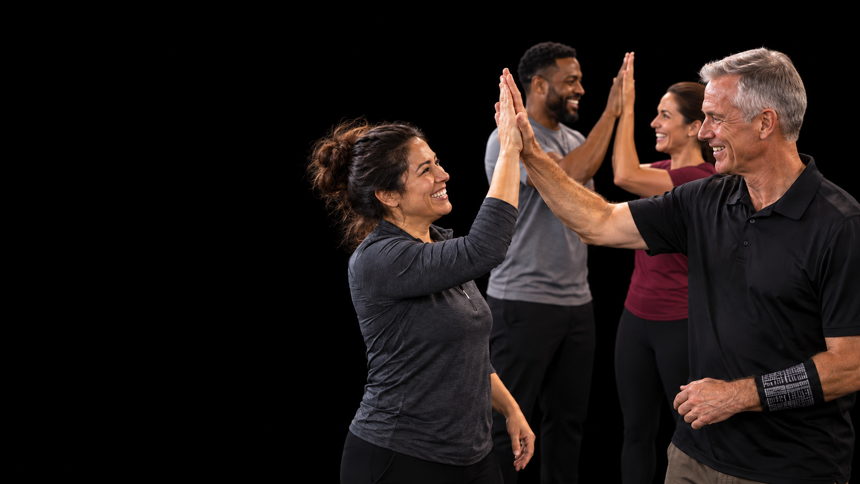 David and three adult students exchange high-fives against a plain black background.